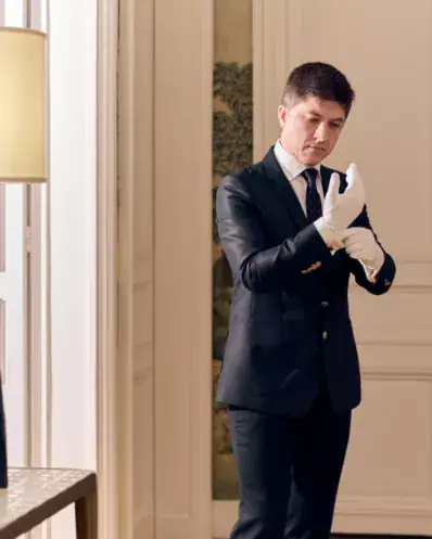 Un intendant de maison en train d'ajuster ses gants avant de commencer son service