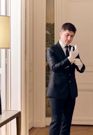 Un intendant de maison en train d'ajuster ses gants avant de commencer son service