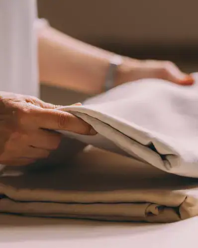 Une ling&egrave;re Maison Helya plie soigneusement des draps en soie