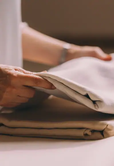 Une lingère Maison Helya plie soigneusement des draps en soie