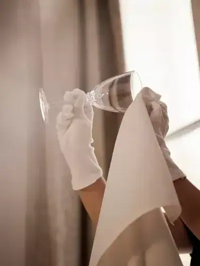 Un maître d'hôtel Maison Helya nettoie soigneusement un verre en cristal
