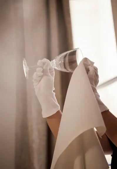 Un maître d'hôtel Maison Helya nettoie soigneusement un verre en cristal